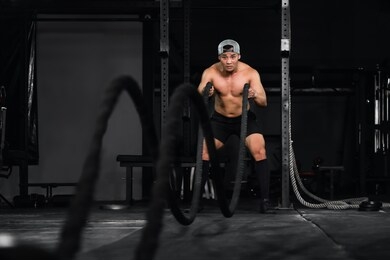 asian athletics bodybuilder workout and exercise with battle rope in gym and fitness club