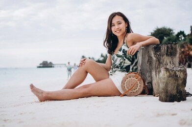 asian woman sitting on white sand by the indian ocean