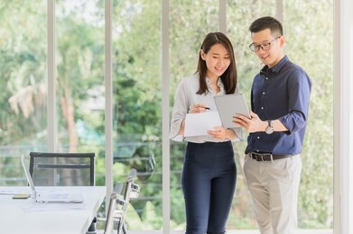 entrepreneur asian businessman and woman discussing new business project in tablet in modern meeting room