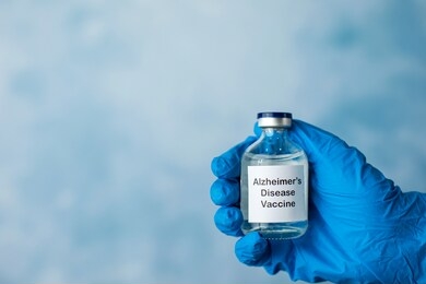 a bottle of a clear medicine vaccine cure for alzheimer's disease being held by a hand with a surgical glove