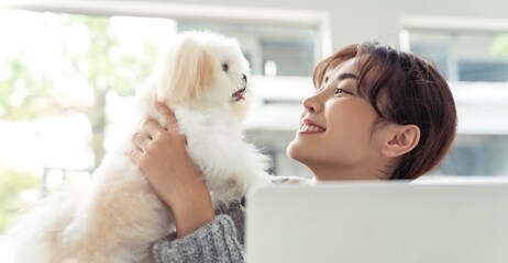 young asian woman holding her cute small pet dog showing adorable relationship between them.