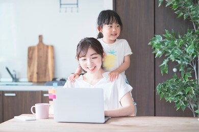 asian woman doing telework in home room while playing with her daughter