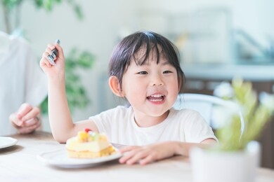 asian mom and daughter eating cake at dining table at home