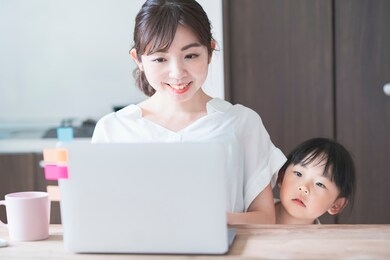 asian girl snuggling up to mom teleworking at home