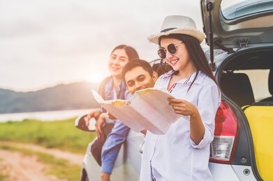 happy asian woman and her friends standing by car. young girl having fun during road trip. people lifestyles and travel vacation concept. friendship journey and outdoor tour. travel bubble theme