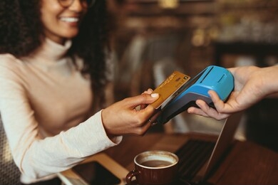 woman making a contactless card payment in a coffee shop. female customer paying using her credit card in a cafe.