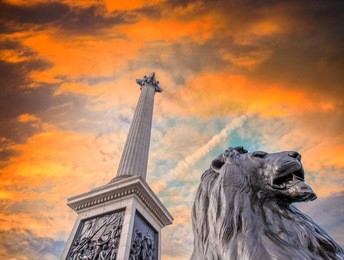 lion statue at trafalgar square against dramatic sky, london, uk.