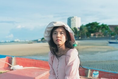an asian woman wearing a hat feels good by the beach.enjoying nature