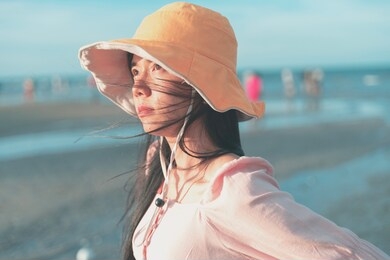 an asian woman wearing a hat feels good by the beach.enjoying nature