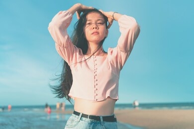 an asian woman wearing a hat feels good by the beach.enjoying nature