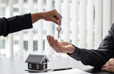 sales manager or real estate agent holds the key handing it to the customer after signing the house purchase contract with home insurance, trading of mortgages and insurance concept.