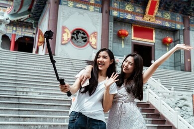 two asian women having wonderful time recording vlog together at chinese temple.