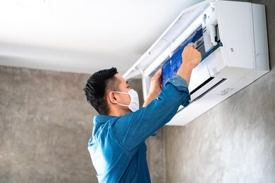 technician man repairing ,cleaning and maintenance air conditioner on the wall in bedroom or office room.on site home service,business ,industrial concept.