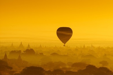 hot air balloon over plain of bagan in misty morning, myanmar