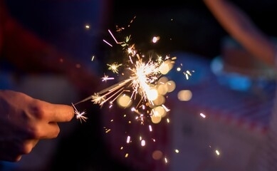 hand holding a sparkler during blue hour in the backyard at a family celebration