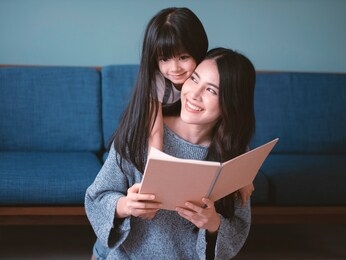 mother and daughter asia hugging and read a book.