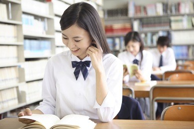  japanese high-school girls opening a book in the library