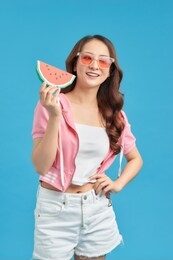 young woman holding big slice of sweet watermelon, posing isolated over blue background,