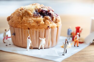 miniature people worker muffin food cake on wooden table use for background sweet food desserts