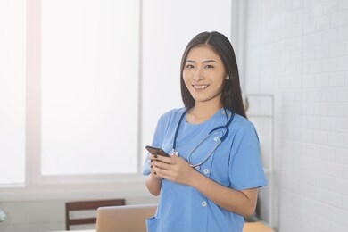 asian doctor female stethoscope looked at phone in er hospital ,or,operating theatre,surgical room,healthcare and medical concept,stethoscope on neck ,medical technology   electronic medical record