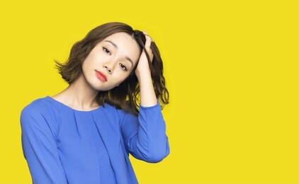 beauty concept of a young asian girl. hair care. skin care. yellow background.