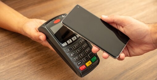 mobile payment, smart phone nfc, near field communication wireless technology. cashier and customer hands with pos machine and smartphone, closeup view