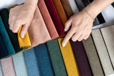 the woman points to the colored fabric that she likes, she chooses the fabric in the catalog with fabric samples for her new sofa. flat lay
