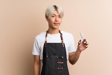 young asian man over isolated background with hairdresser or barber dress