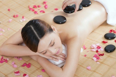 	a young lady enjoying stone massage at spa	