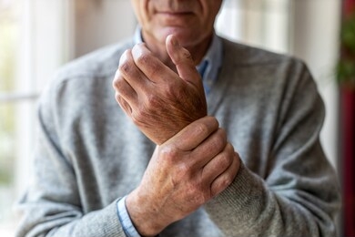 senior man with arthritis rubbing hands
