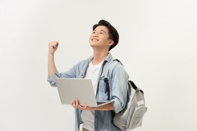 winning asian college student with laptop in his hand isolated on white background