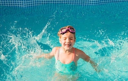 little happy girl swims in the pool. summer holidays. girl in a swimsuit and swimming glasses.