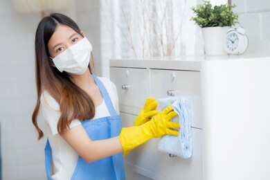 young asian woman in face mask and gloves cleaning home in room, housekeeper is wipe with fabric, housemaid and service, worker polish dust in house, housework and domestic, lifestyle concept.