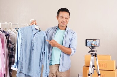 asian man video live streaming sell shirt e commerce store or blogger live broadcasting selling shirt by smartphone and sharing on social media by at home