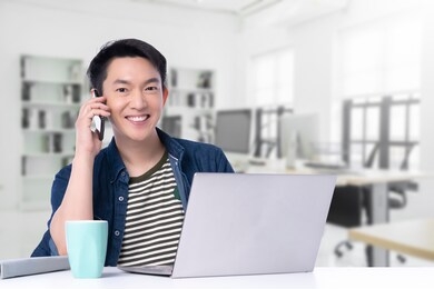 attractive asian entrepreneur working with laptop smartphone with confident and cheerfulwith modern interior office workplace background