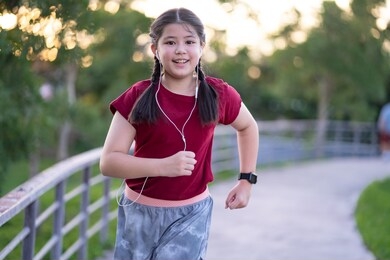 pre teen asian girl exercising outdoors at sunset running towards camera energetically