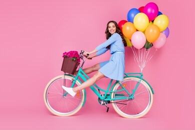 full length body size profile side view of attractive cheerful cheery wavy-haired lady riding bike without legs delivering decoration event having fun isolated pink pastel color background