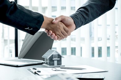 a real estate agent and clients shake hands after completing the home insurance contract negotiation and signing a formal contract. rental and home insurance concepts.
