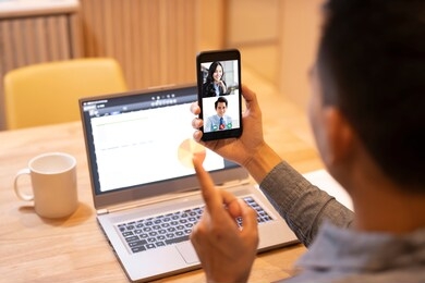 young man working at home and using smart phone with video conference