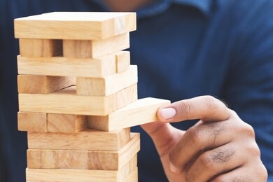 people hand playing take one brown wood block stack game on building tower. concept planning risk and strategy in and engineer construction. 