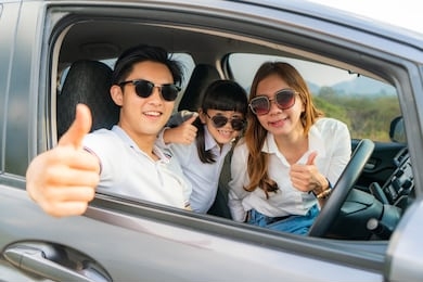 happy asian family with father thumb up and mother and daughter wear sunglass in compact car are smiling and driving for travel on vacation. car insurance or rental 