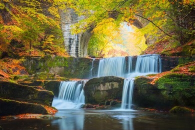 fall autumn landscape - river waterfall in colorful autumn forest park with yellow red leaves with old bridge