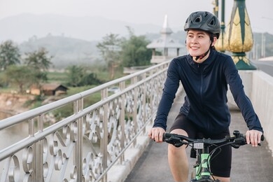 young asian cyclist woman exercise by riding a bicycle outdoor. biking is a top-notch cardio workout. plus it strengthens your lower body, including your legs, hips, and glutes.
