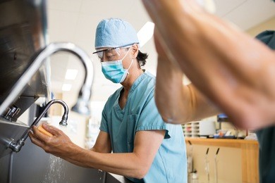 surgeons scrubbing hands and arms before surgery in hospital