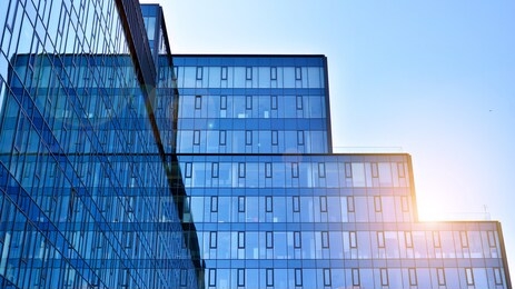 facade texture of a glass mirrored office building. fragment of the facade. bottom view of modern skyscrapers in business district in evening light at sunset with lens flare filter effect.