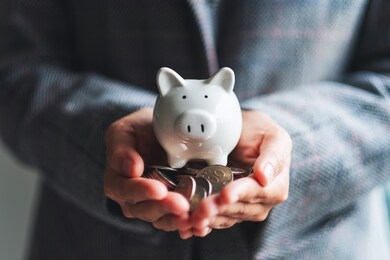closeup image of a woman holding piggy bank and coins in hands for saving money and financial concept