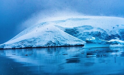 snowing blue glacier snow mountains paradise bay skintorp cove antarctica. glacier ice blue because air squeezed out of snow.