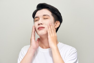 handsome man with clay mask on his face against white background