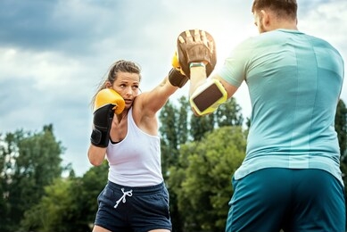 beautiful handsome healthy woman sparring with a boxing partner outdoors. couple in park boxing.