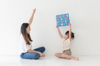 young asian mother taught her little daughter about reading english characters, having fun, having fun together. in a comfortable cozy house on the weekend, family concept